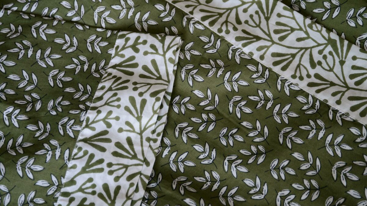 a close up of the lightweight cotton kimono with a block print leaf design in olive green and white and with contrast belt and cuffs