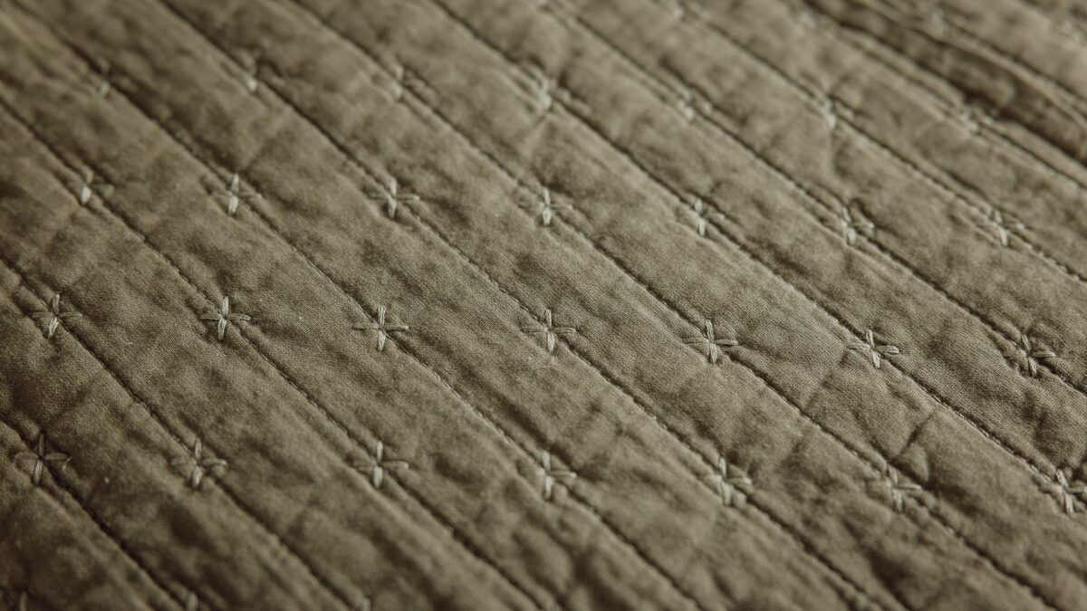 olive green quilt with embroidered cross detail