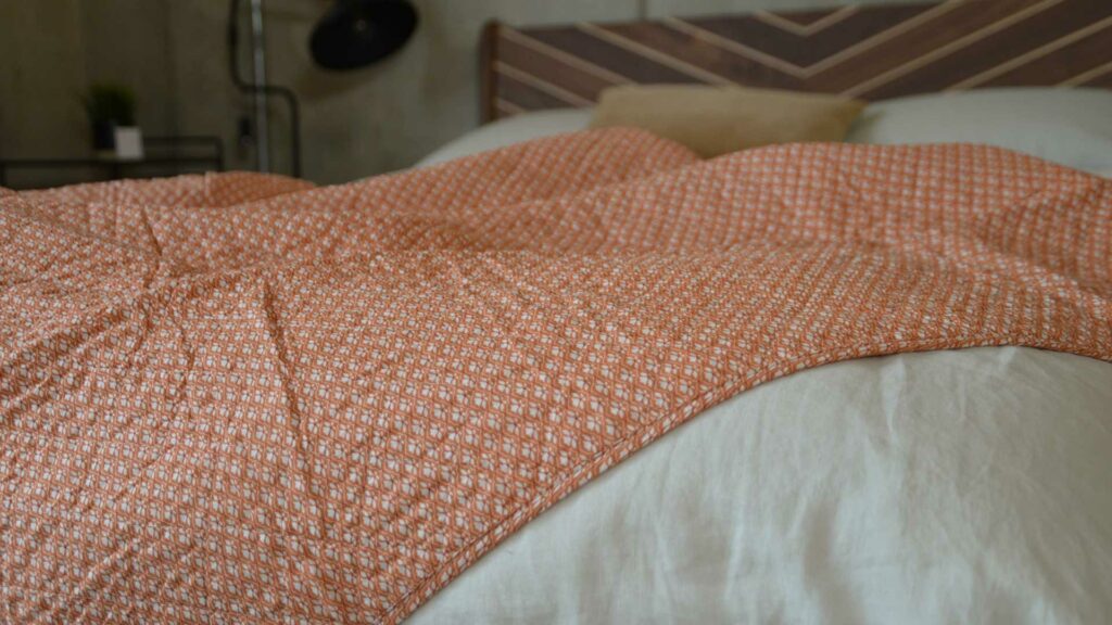 orange quilted throw with a delicate ivory flower pattern