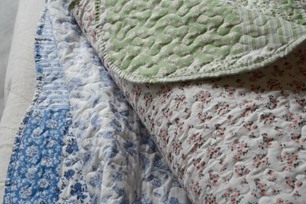 Reversible quilted bedspreads in Blue and Green colours, floral design one side and patchwork patterns the other