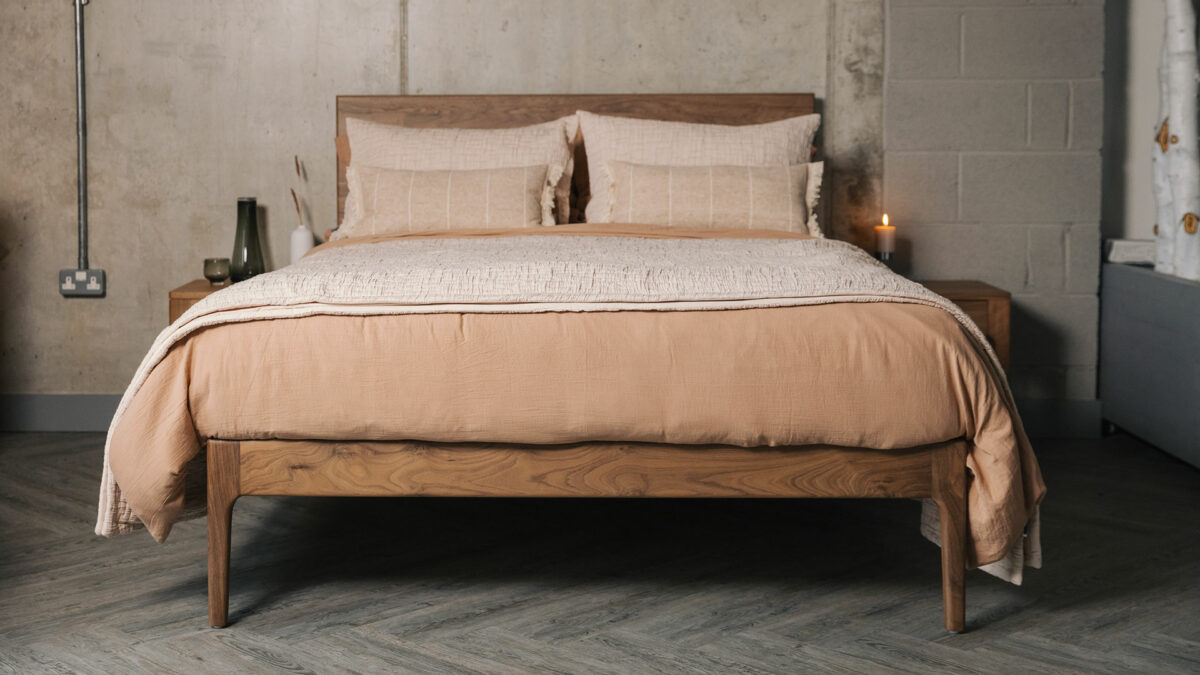 Chiswick bed in solid walnut shown with terracotta coloured bedding