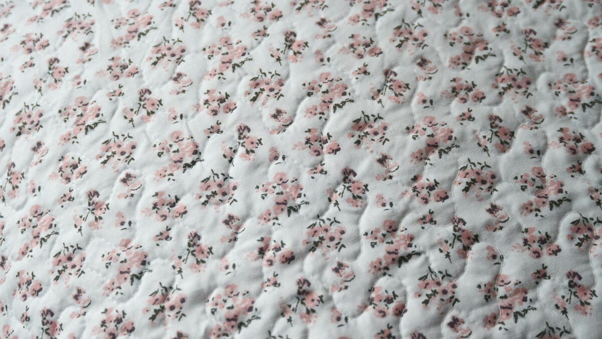 reversible quilted bedspread with rose coloured floral print one side and sage and rose patchwork designs on the other