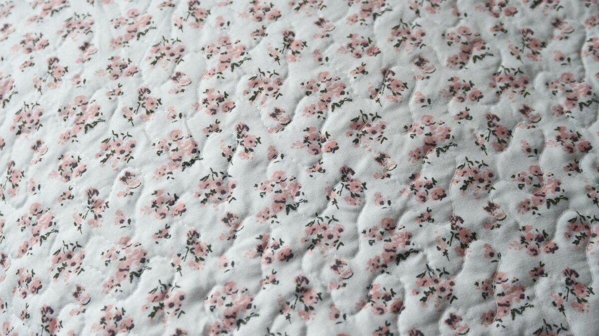 reversible quilted bedspread with rose coloured floral print one side and sage and rose patchwork designs on the other