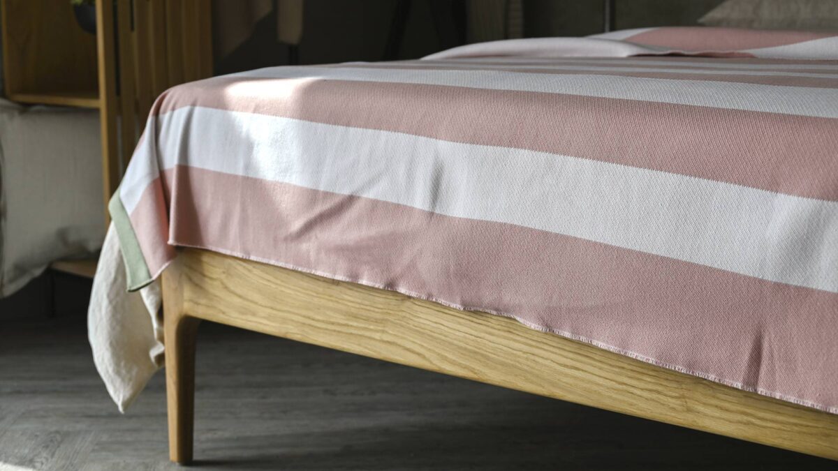 pink and white striped throw over the foot of a bed.