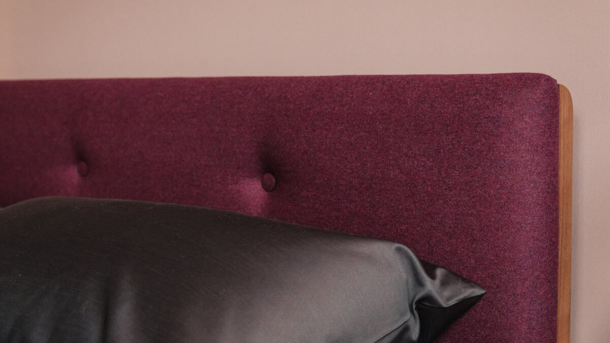 plum coloured upholstered headboard with 1000 thread count bedding