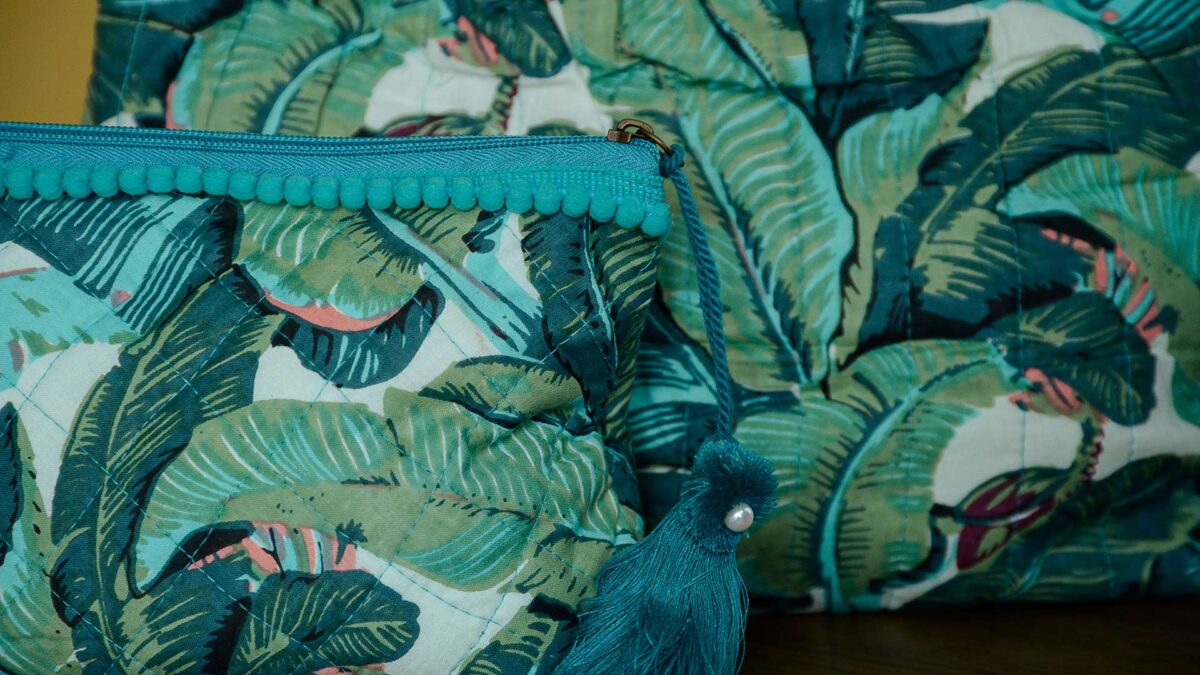 close up on blue and green tropical print toiletry bags with large tassel with pearl detail.