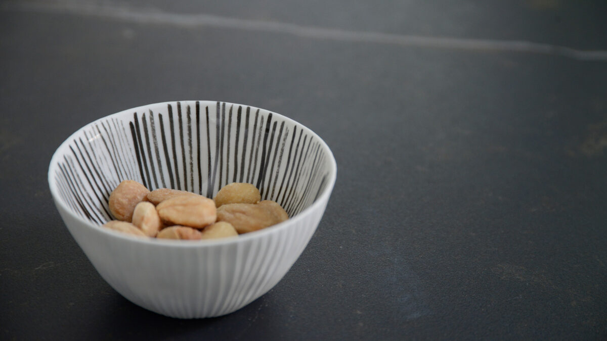 small ribbed porcelain bowl with painted grey stripes to the inside shown used as a snack bowl