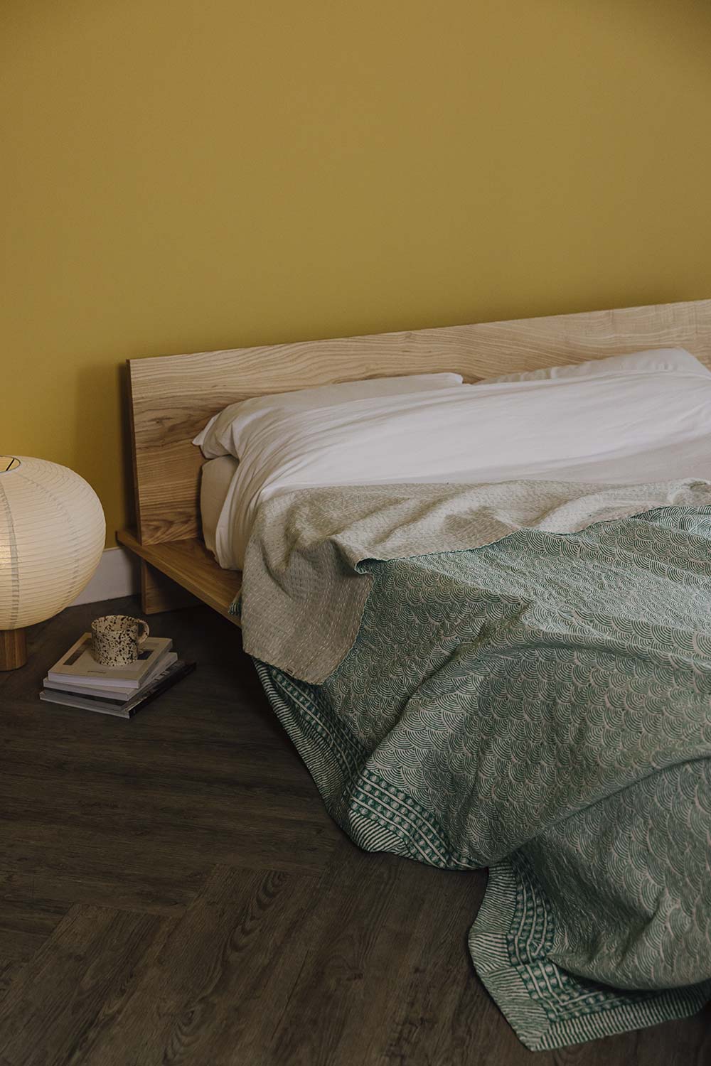 Portrait image of rumpled green kantha bedspread with wave pattern on ash Oregon bed base.