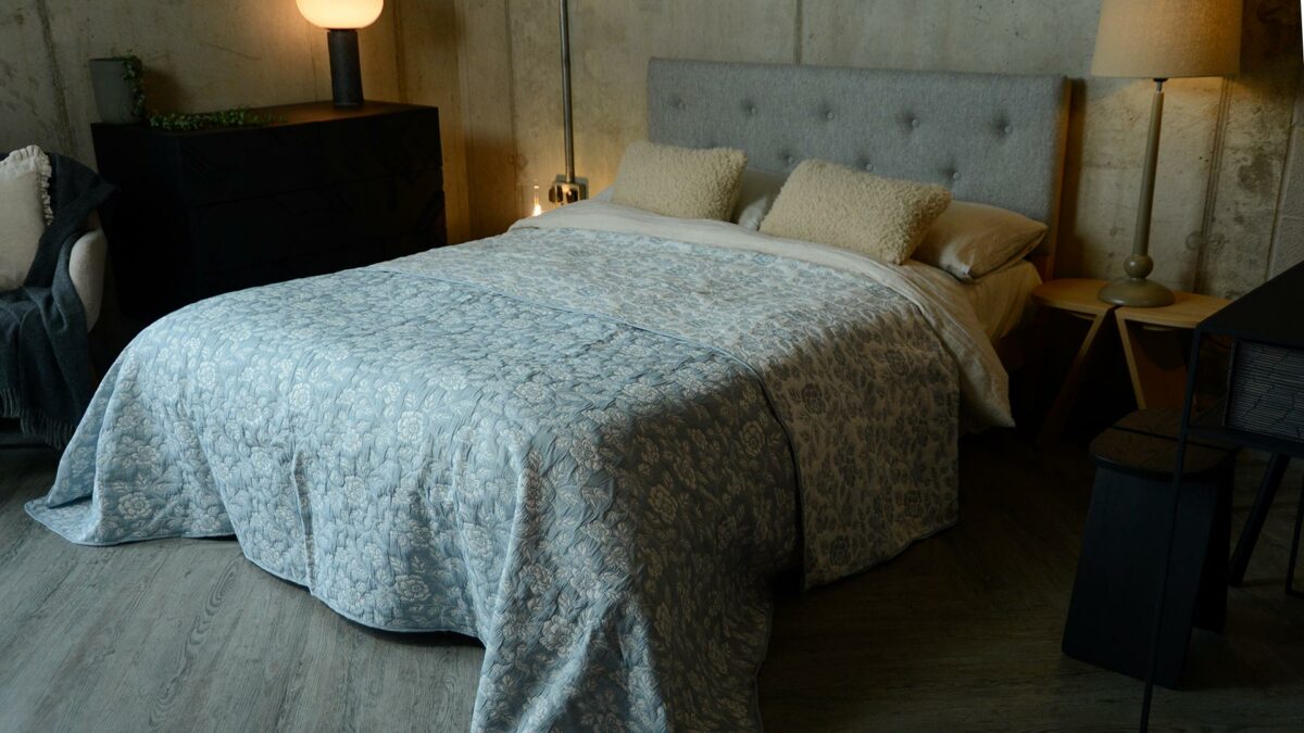 Wedgwood blue and ivory floral patterned reversible quilted bedspread shown on a king-size bed