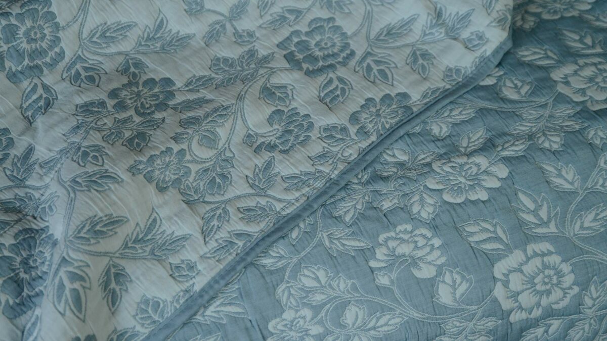 Wedgwood blue and ivory floral patterned reversible quilted bedspread a picture showing both sides