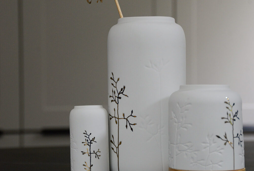 white porcelain vases with gold sprig motif and with matching candle lantern with a wooden base