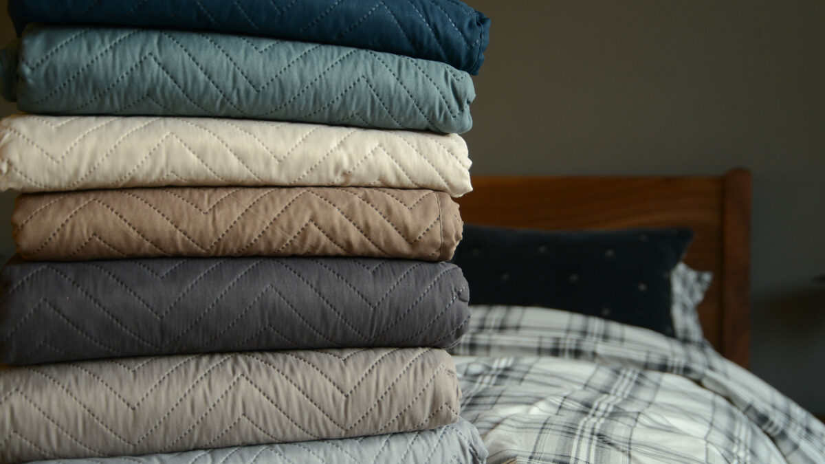 chevron pattern lightly quilted bedspreads stacked and in a range of colours