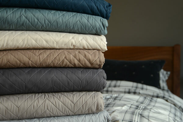 chevron pattern lightly quilted bedspreads stacked and in a range of colours