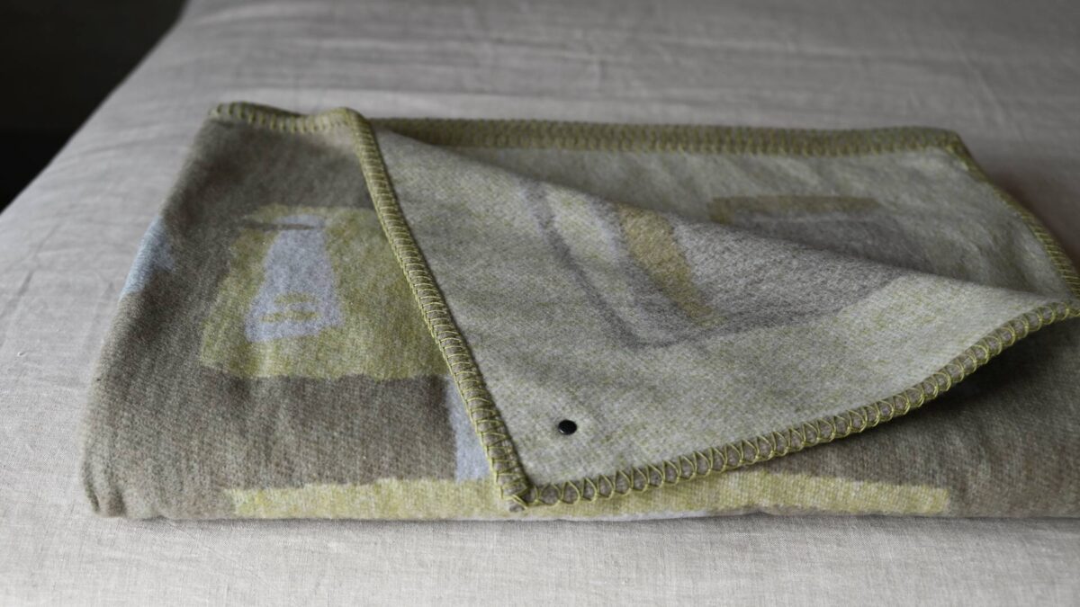 sage green abstract patterned throw neatly folded.