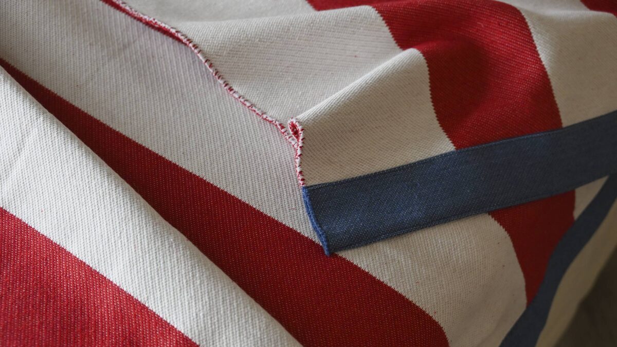 close up of a red and ivory striped blanket with a dark blue edge.