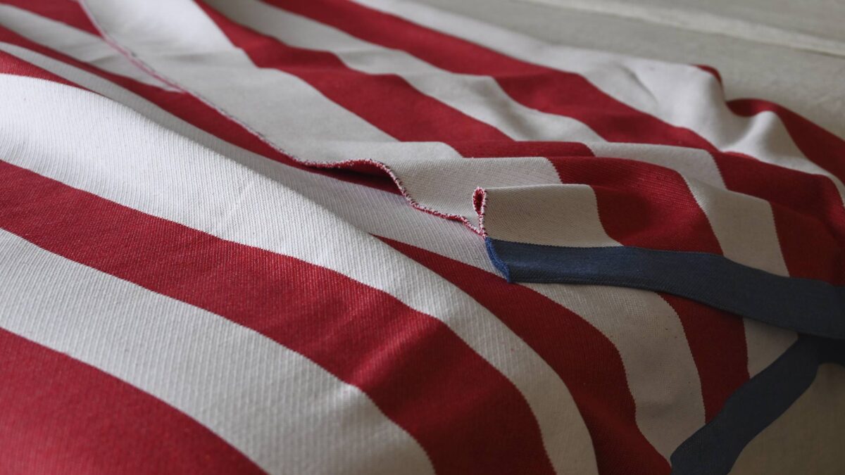 close up of a red and ivory striped blanket with a dark blue edge.