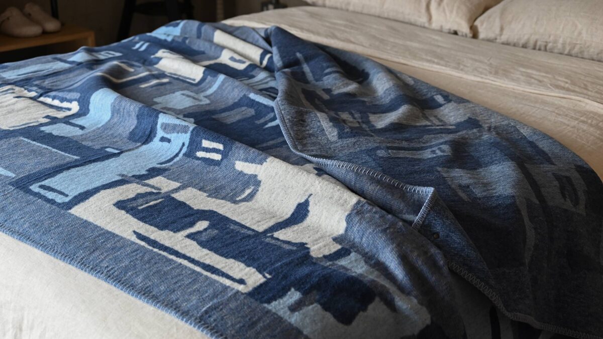 abstract patterned blue throw draped over stone bedding.