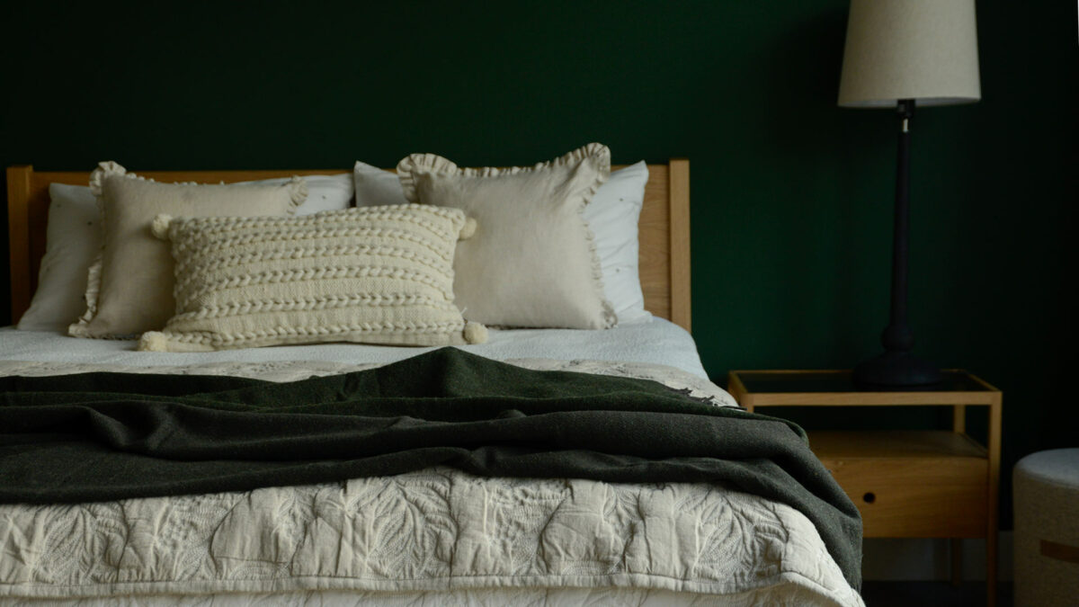 reversible pure wool throw in Fir Green shown on a bed