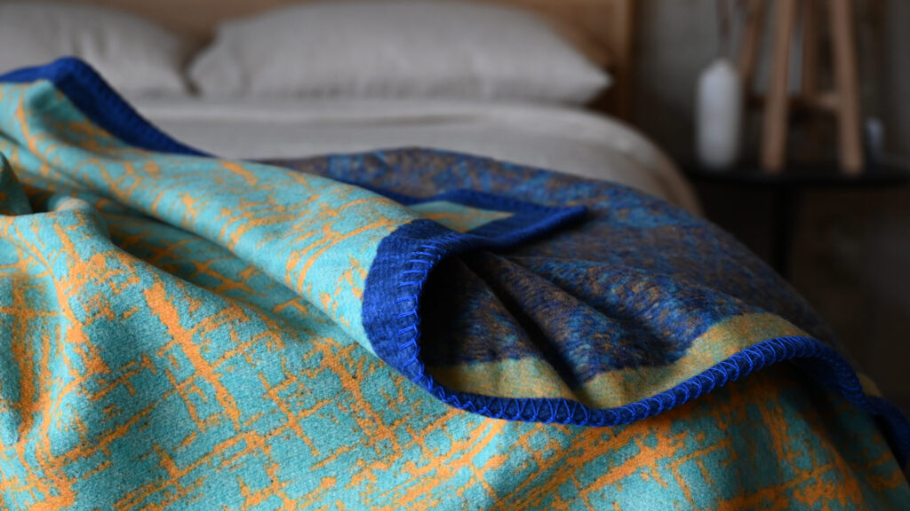 Aqua throw with blue border and orange crosshatch pattern.