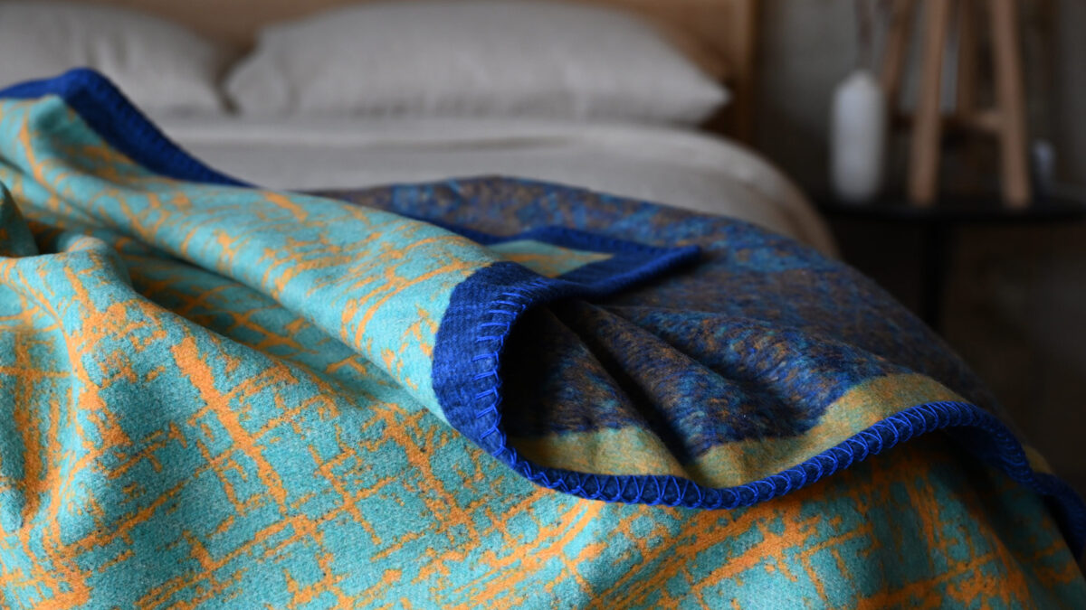 Aqua throw with blue border and orange crosshatch pattern.