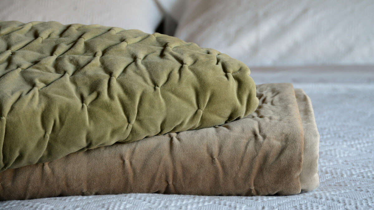 sage green and light brown softly quilted velvet bedspreads shown together