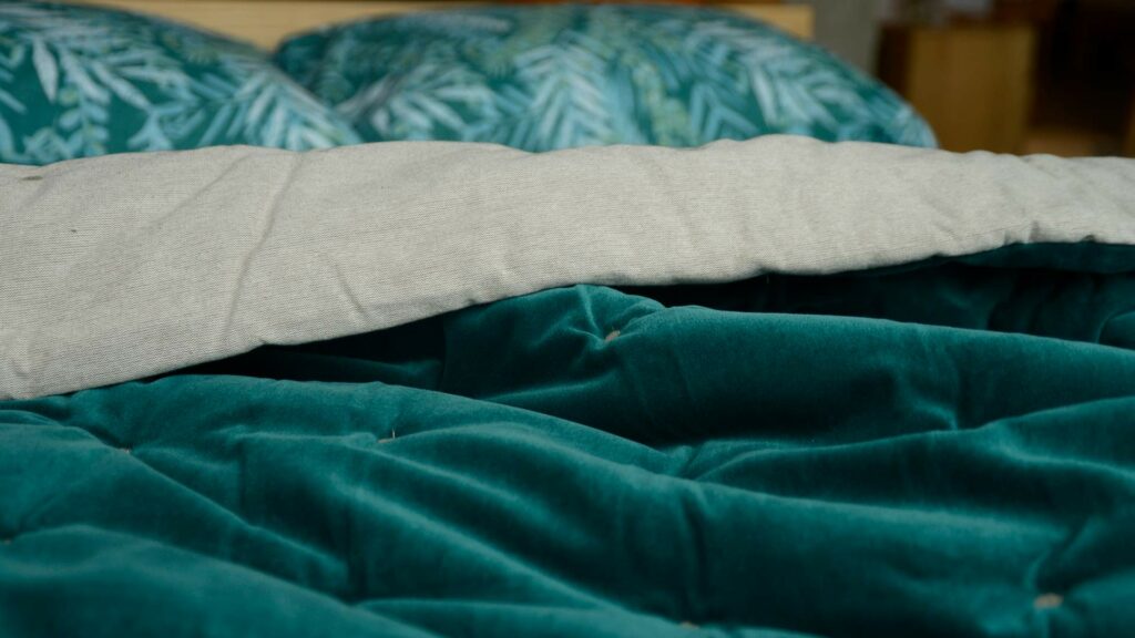 reversible quilted throw in teal coloured velvet and linen like cotton.