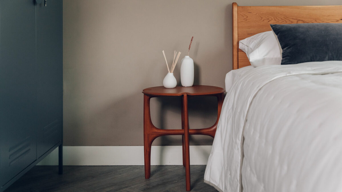 rich toned retro inspired mahogany side table shown as a bedside