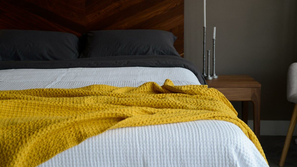 waffle weave cotton throw in a turmeric yellow colour shown on a kingsize bed