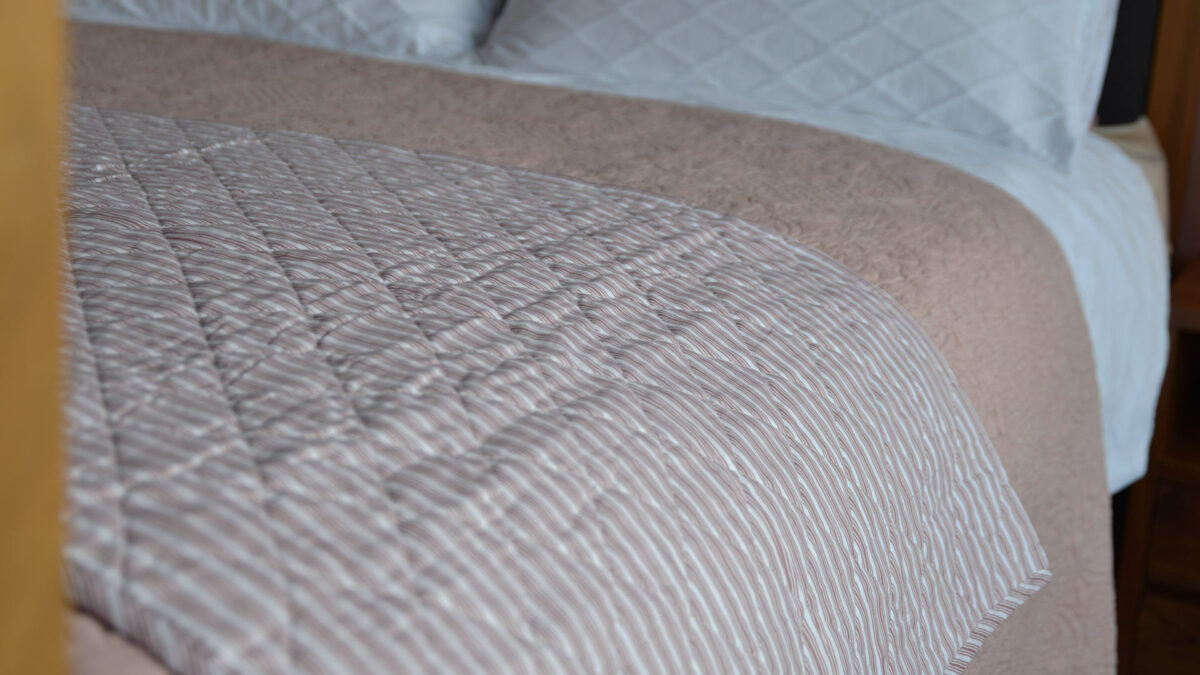 rose multi stripe quilted throw on bed