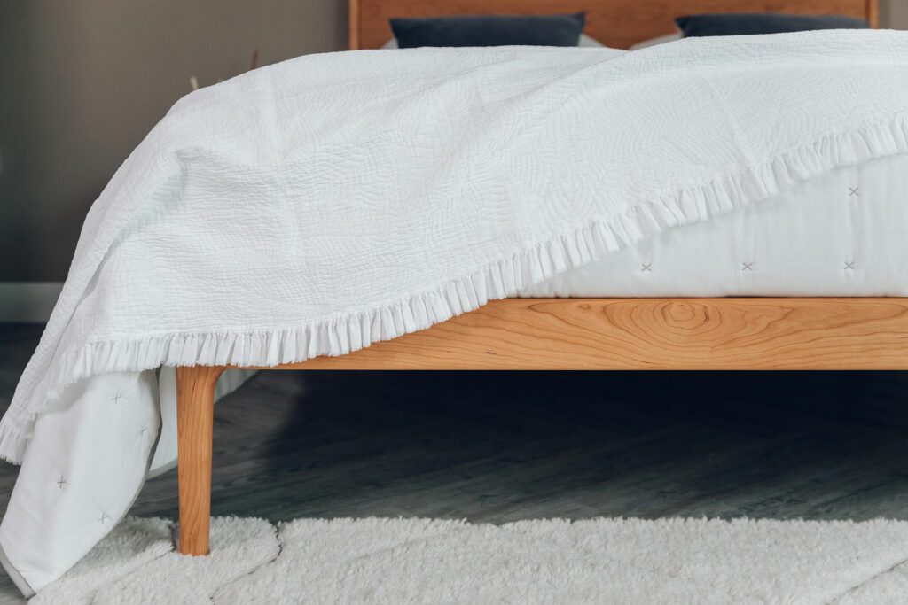 textured ruffle edged bedspread in white shown draped on a bed