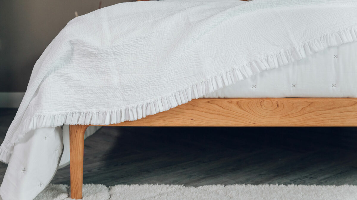 textured ruffle edged bedspread in white shown draped on a bed