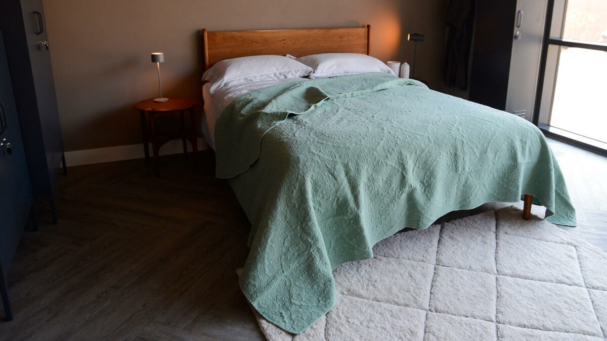 floral embroidered quilted bedspread in sage green shown on a kingsize bed