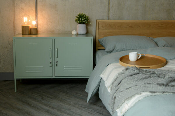 locker style storage cabinet in sage green used as a bedside table