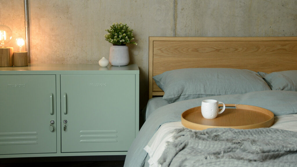 locker style storage cabinet in sage green used as a bedside table