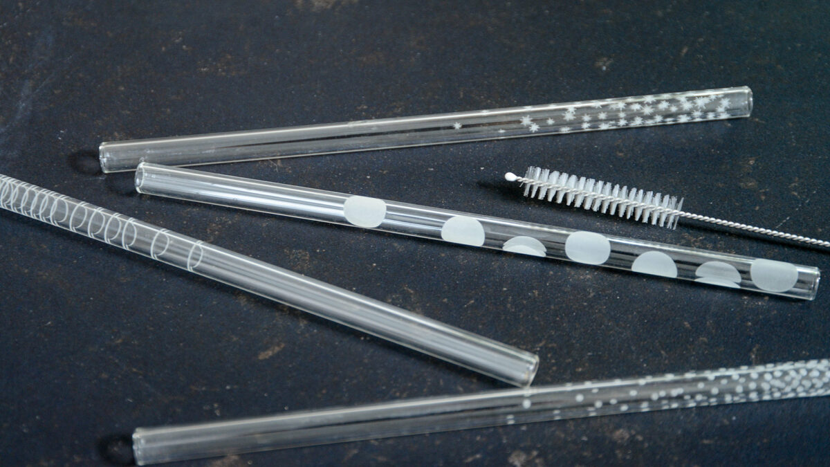 set of patterned glass drinking straws and cleaning brush shown close up