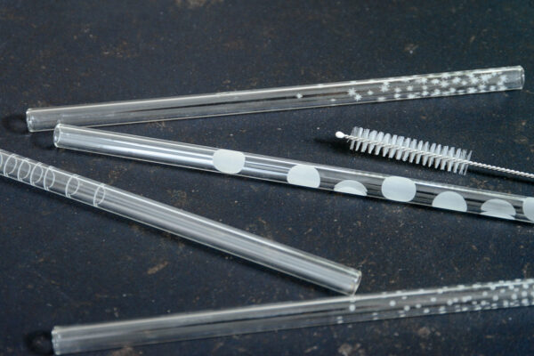 set of patterned glass drinking straws and cleaning brush shown close up