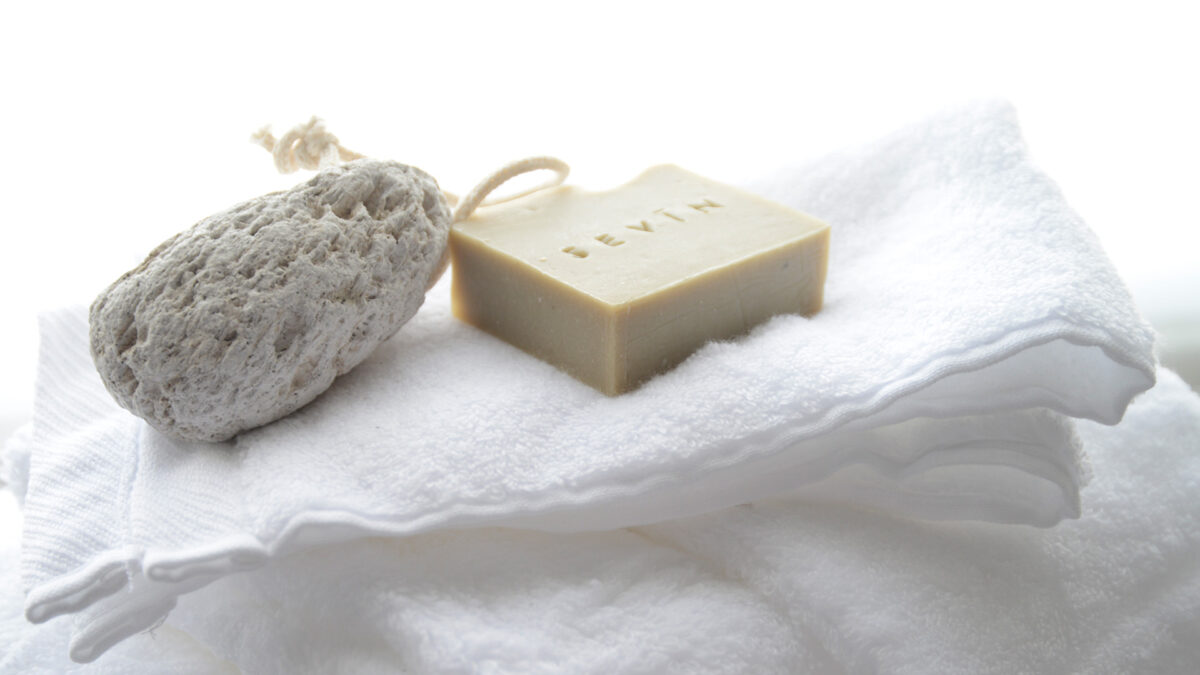 softest fluffy white bathroom towels shown with Sevin soap and pumice stone