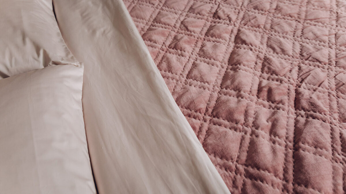 dusky rose coloured quilted velvet bedspread shown with shell pink bedding