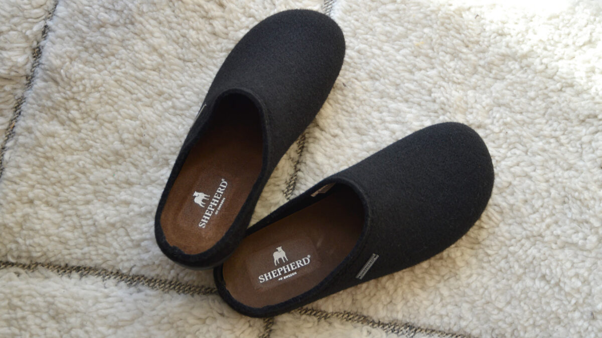 Black mens slippers on white rub. Shepherd logo visible inside.