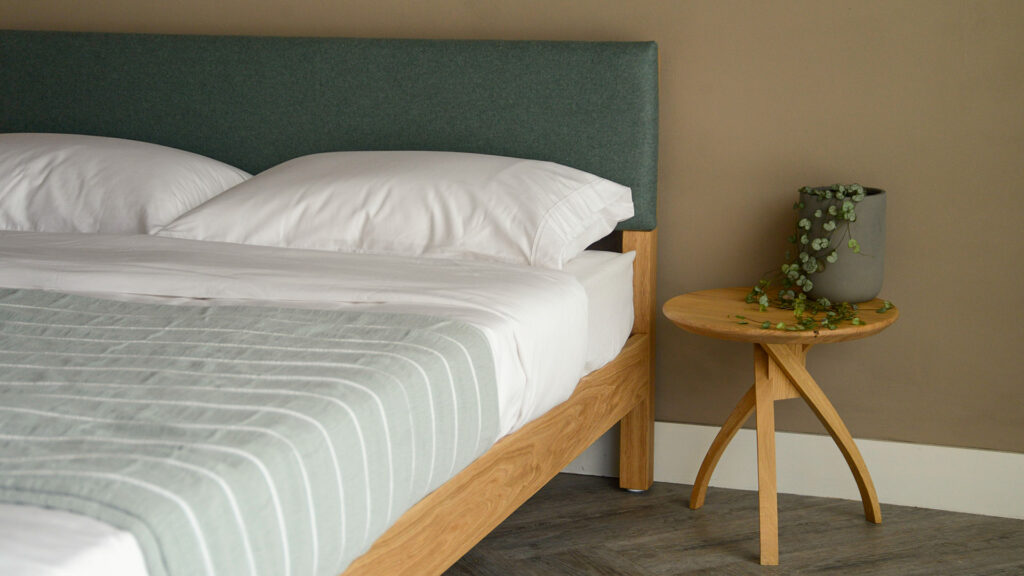 Arran a low wooden bed with upholstered headboard here made from oak