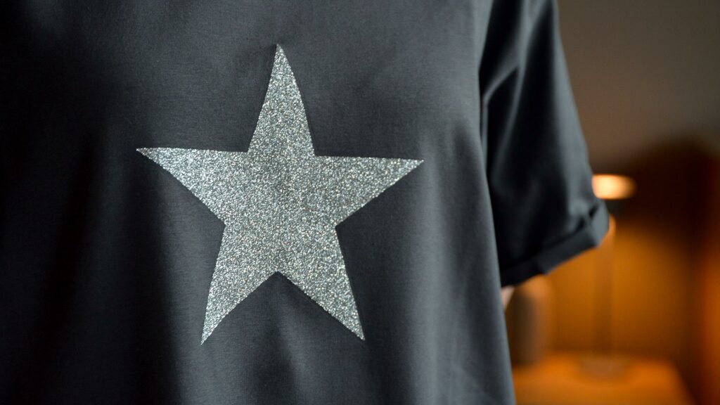 charcoal grey T shirt with silver glitter star motif shown on a model and close up