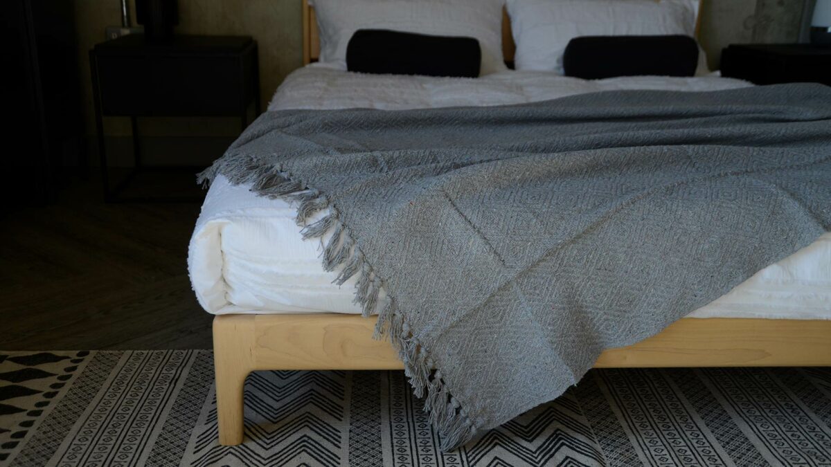 silver grey diamond weave cotton rich throw shown on a kingsize wooden bed