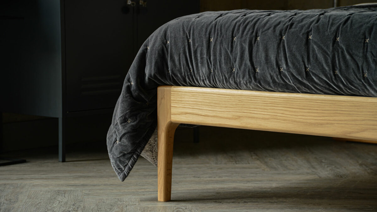 Curved oak bed leg detail with grey slate quilt