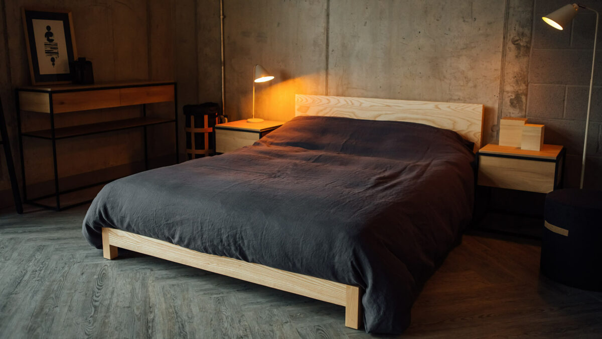 Scandi style bedroom with low pale wood Sonora bed an black framed wooden Monolit console table