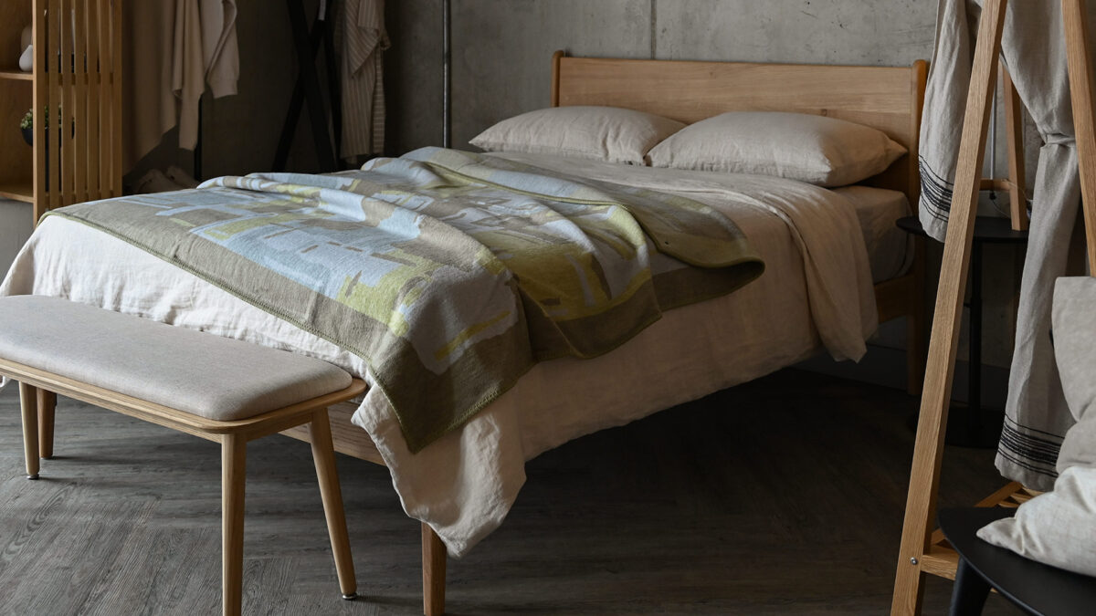 Oak bed with stone bedding. A lime and taupe throw on the top.