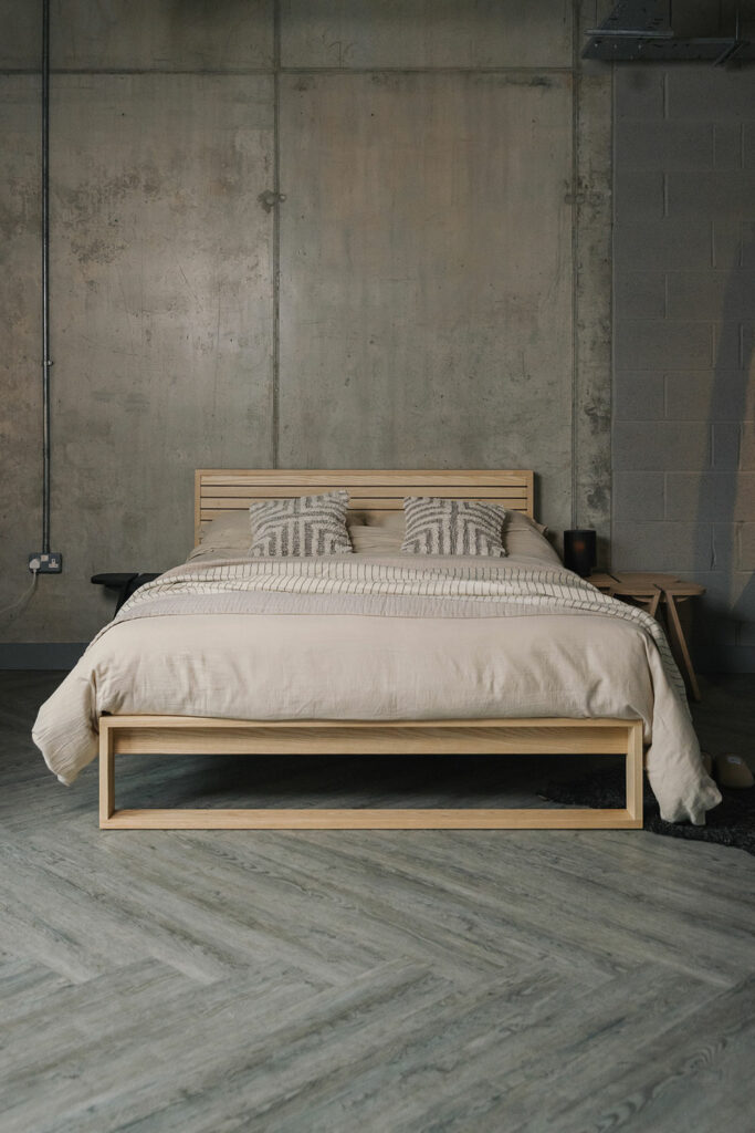 A special edition Leith bed in Ash wood with walnut stripes to the headboard panel dressed in deep cream soft cotton bedding