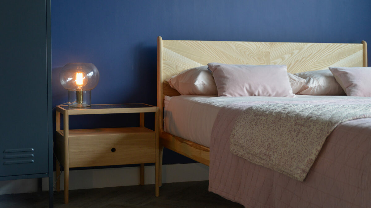 Oak wood Spindle bedside table with a storage drawer and open shelf shown with our wooden Hoxton Bed.