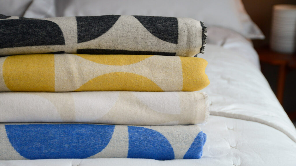 graphic patterned soft cotton throws in a choice of colours shown as a stack