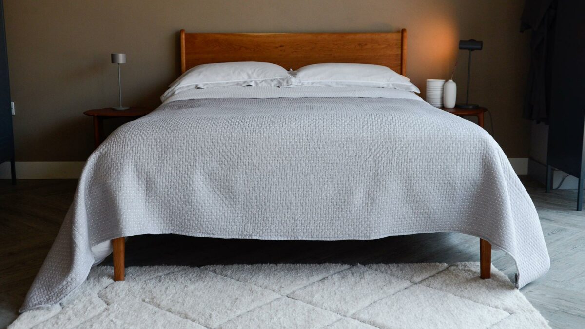 reversible stitched polka dot quilted bedspread in grey and white shown on a kingsize bed