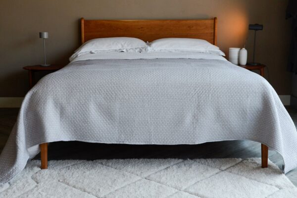 reversible stitched polka dot quilted bedspread in grey and white shown on a kingsize bed